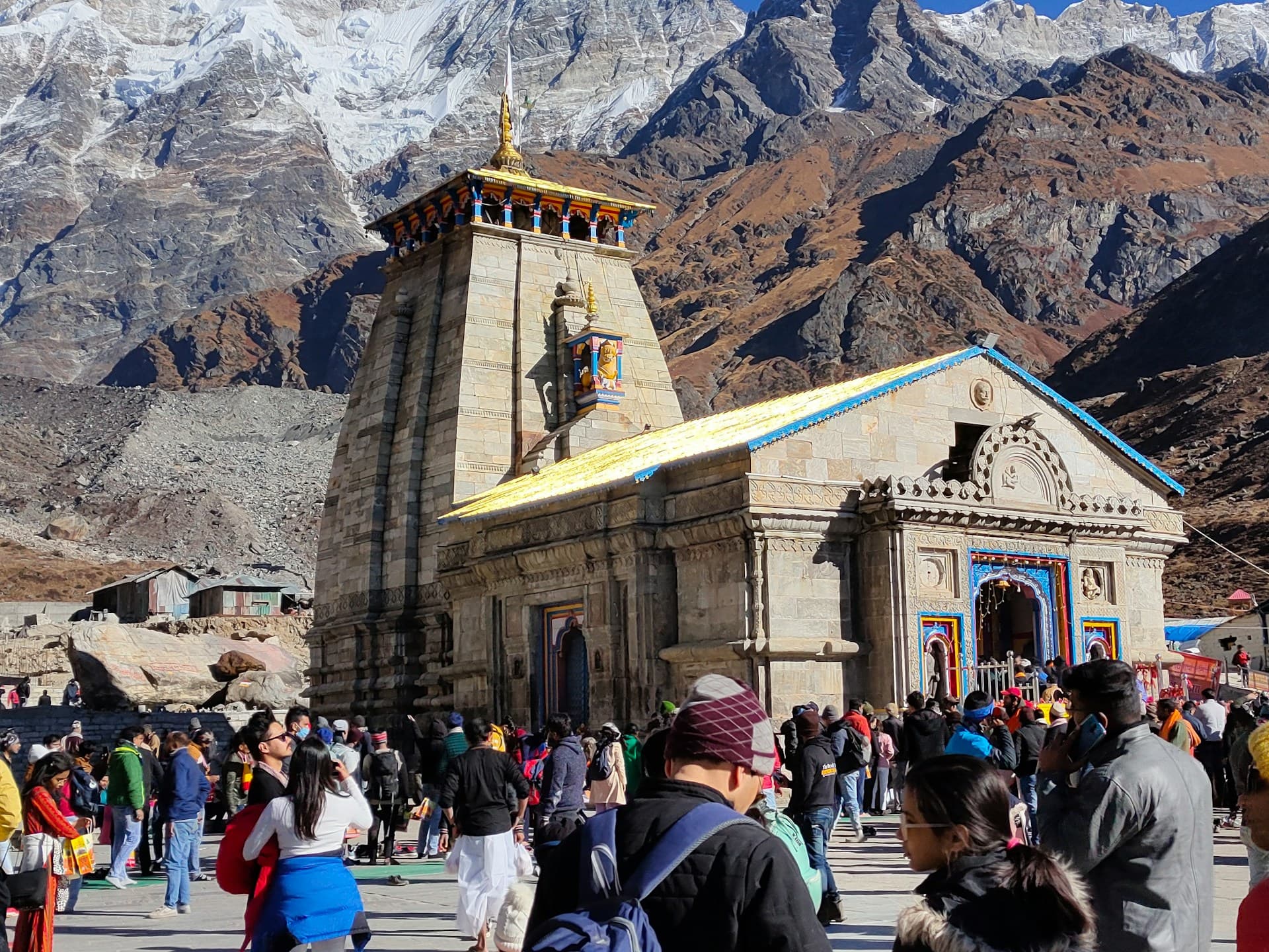 Kedarnath temple with crowds of pilgrims and snow-covered Himalayan peaks in the background during peak season