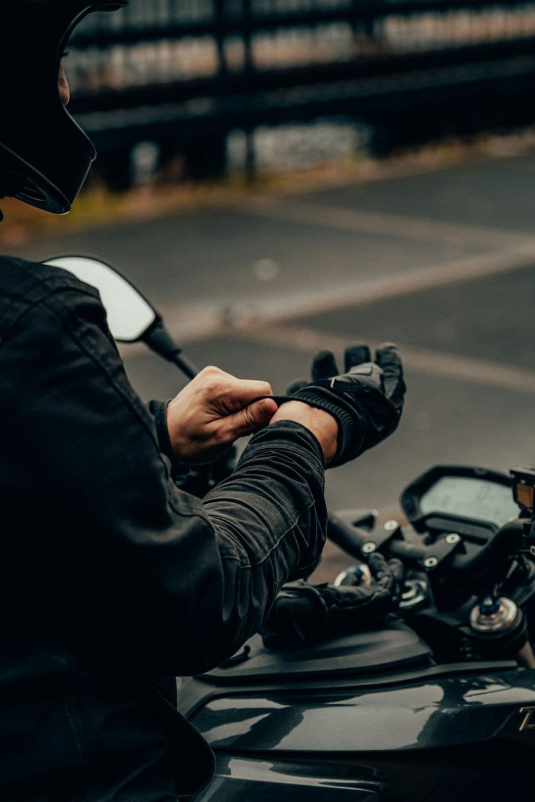 Rider putting on motorcycle gloves next to bike handlebars before a mountain ride