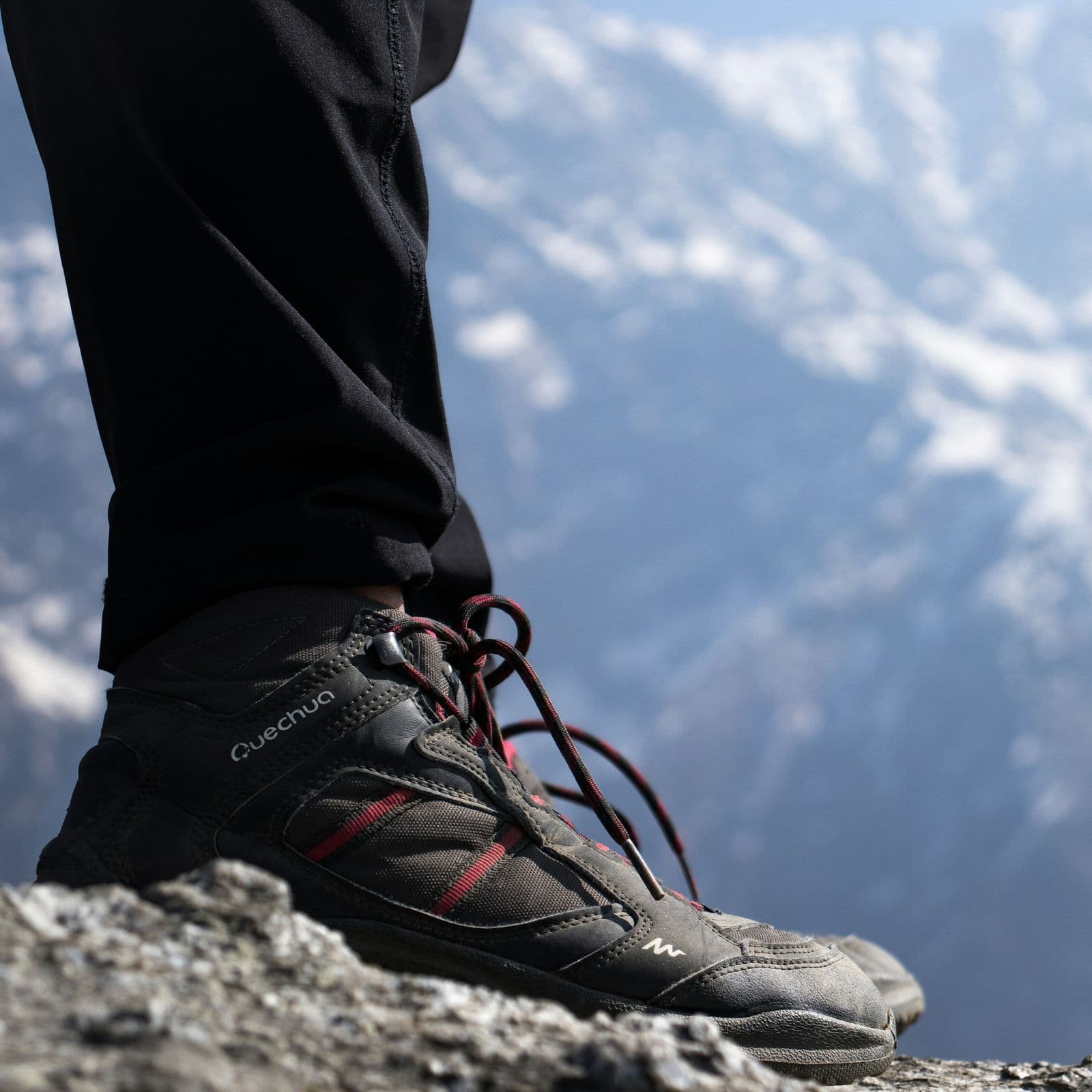 Quechua trekking shoe on a rocky mountain ledge with snow-capped Himalayan peaks behind
