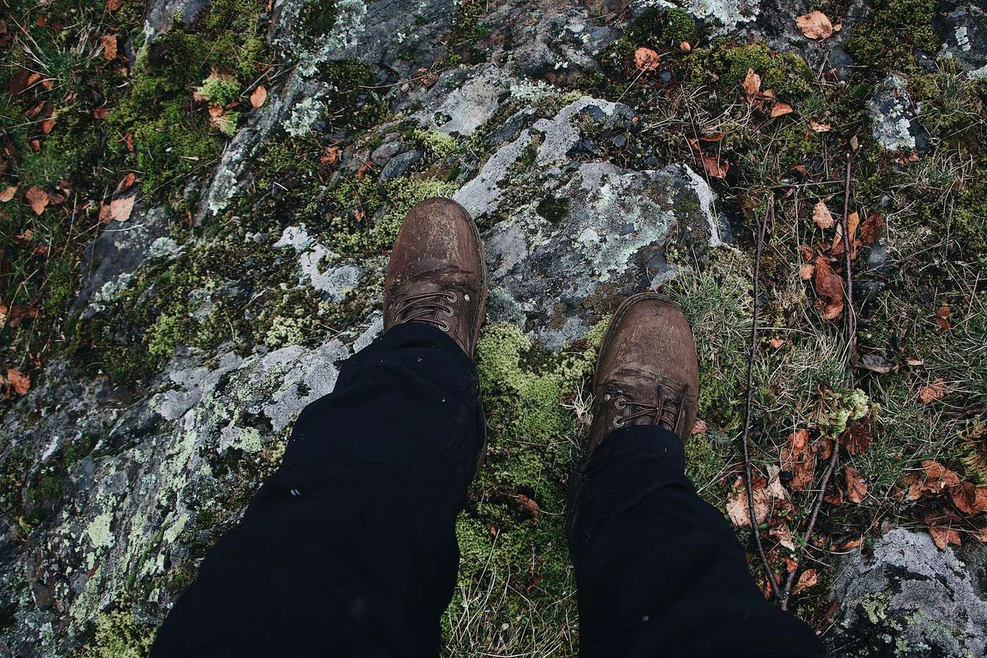 Worn trekking shoes on wet rocky terrain during monsoon conditions
