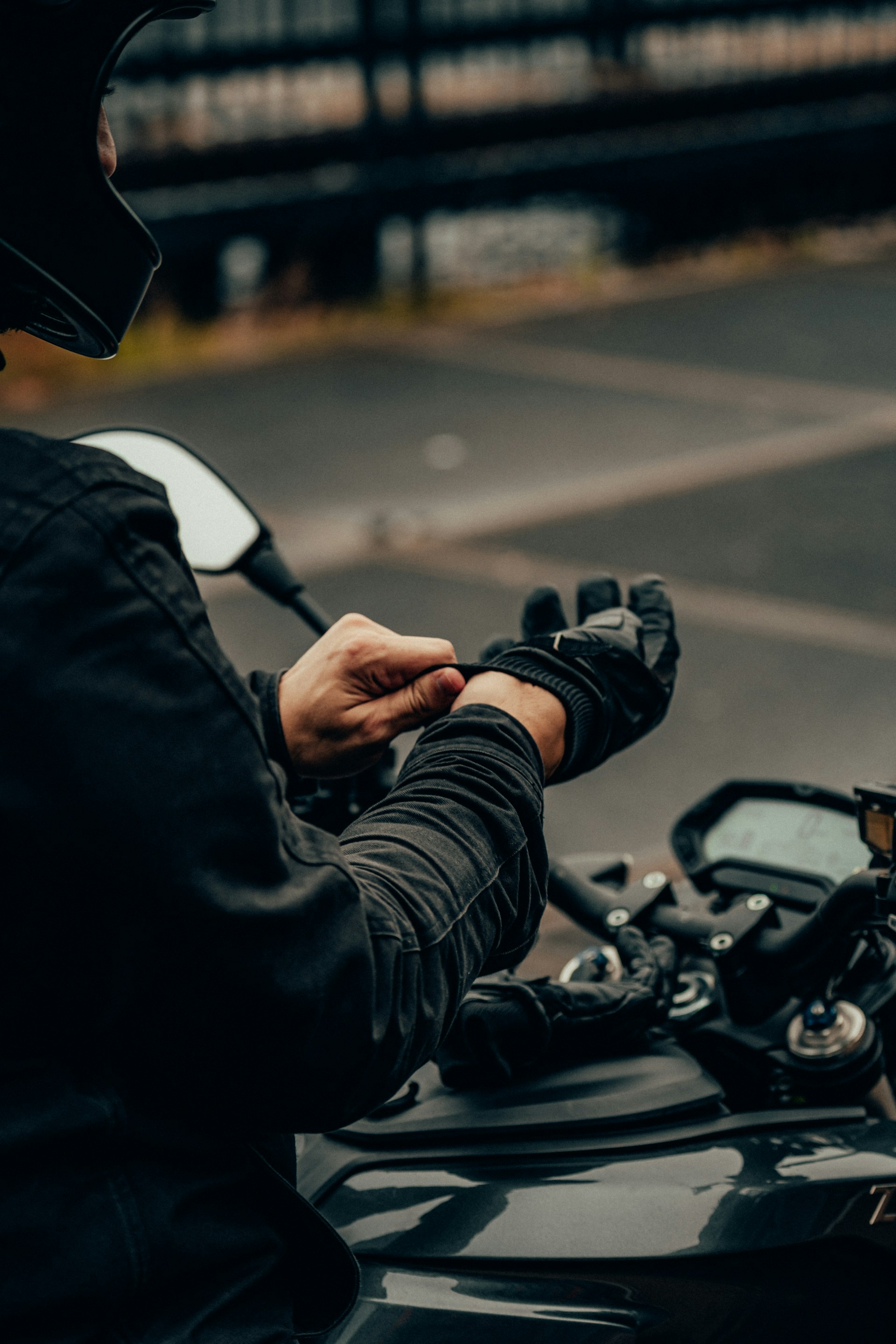 Rider putting on motorcycle gloves next to bike handlebars before a mountain ride