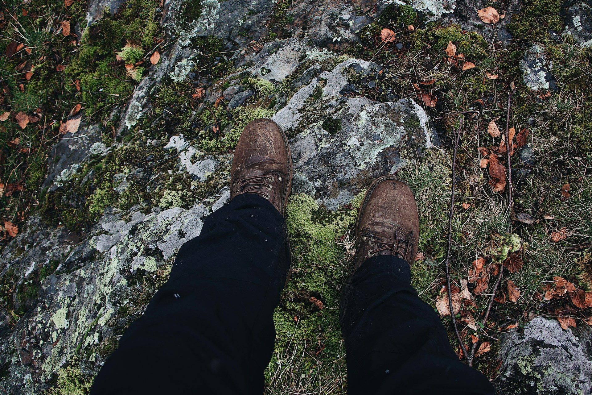 Worn trekking shoes on wet rocky terrain during monsoon conditions